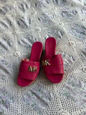 Michael Kors bright pink platform slide sandals with a cork wedge.